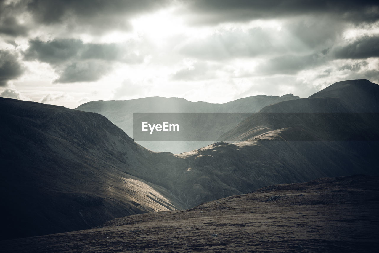 Sunbeams streaming from cloudy sky on mountains