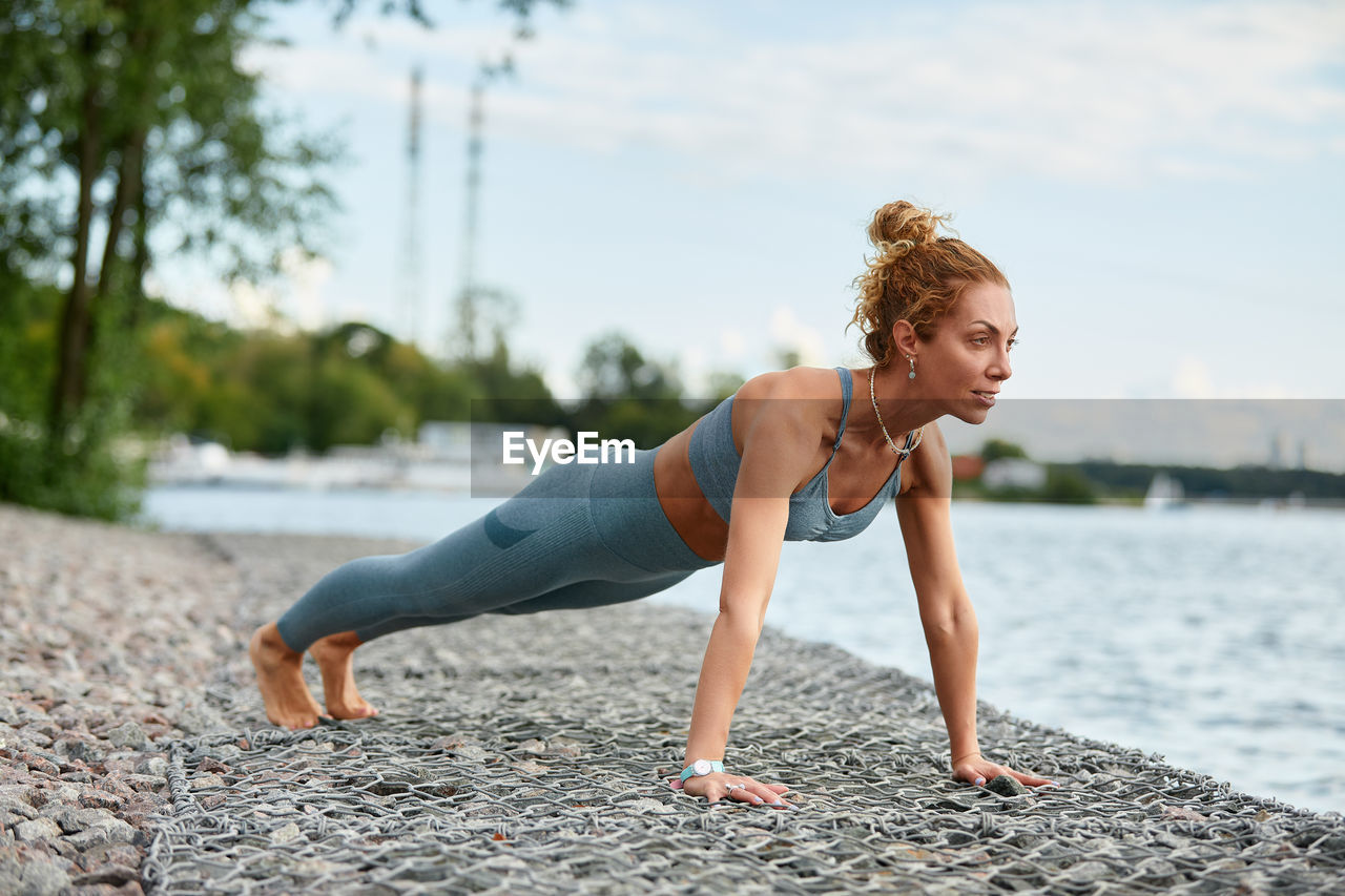 full length of young woman exercising on field