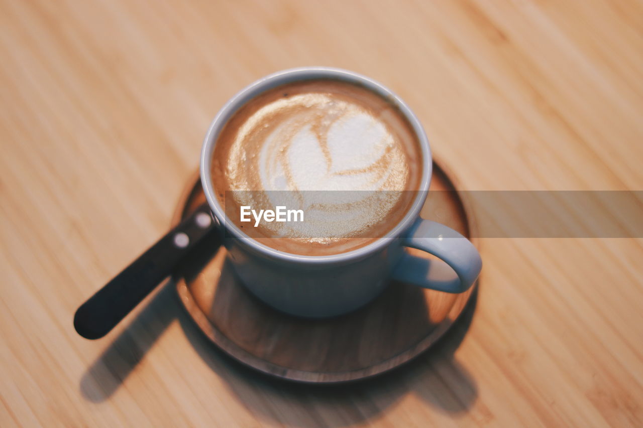 HIGH ANGLE VIEW OF COFFEE CUP ON WOODEN TABLE