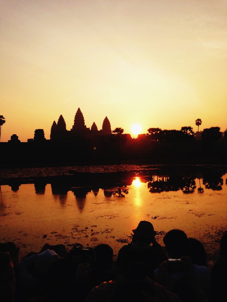 Silhouette angkor wat temples reflecting in water during sunrise