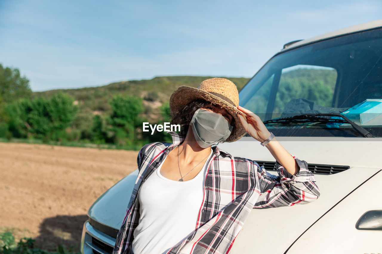 Portrait of woman wearing mask while standing by vehicle