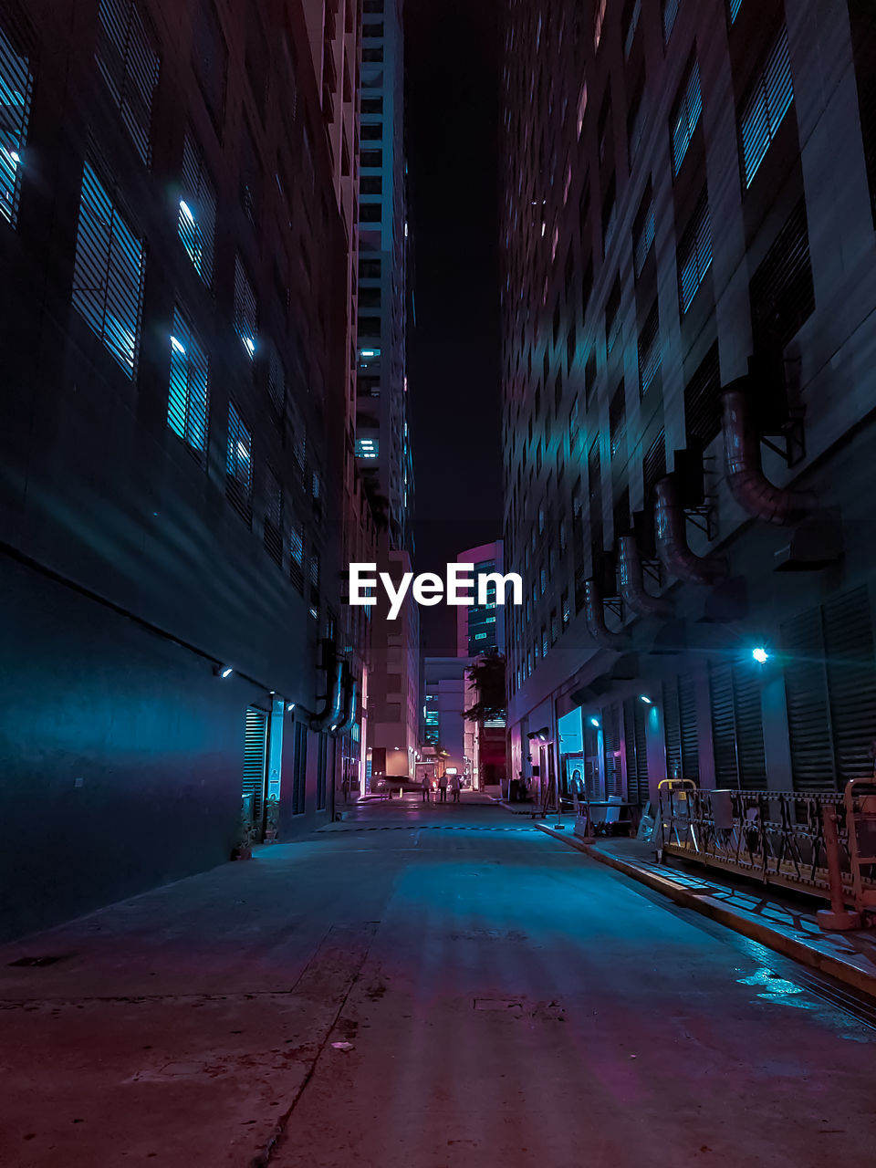 Empty road amidst illuminated buildings in city at night