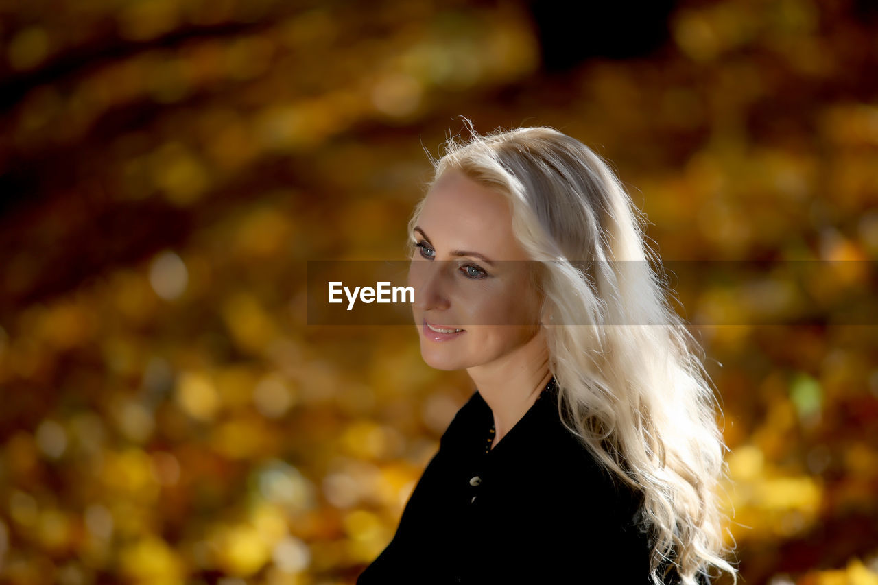 High angle view of smiling young woman standing at park during autumn