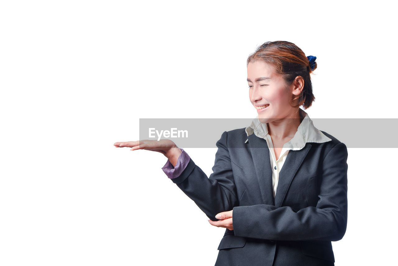 Smiling businesswoman gesturing against white background