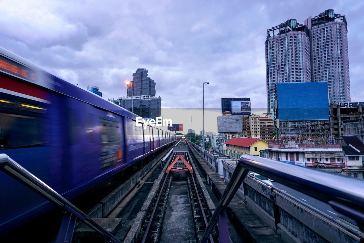 RAILROAD TRACKS AMIDST BUILDINGS AGAINST SKY