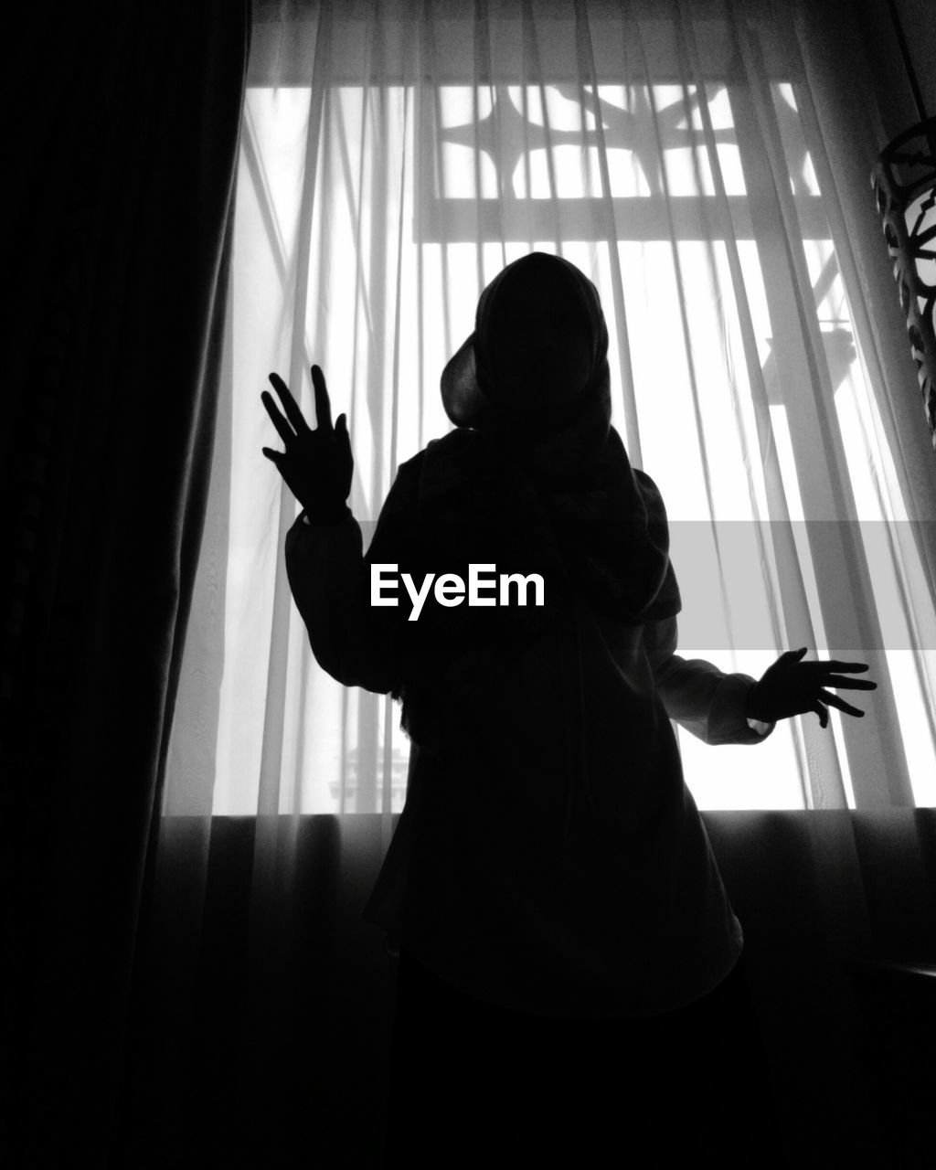 Low angle view of silhouette woman standing by window at home