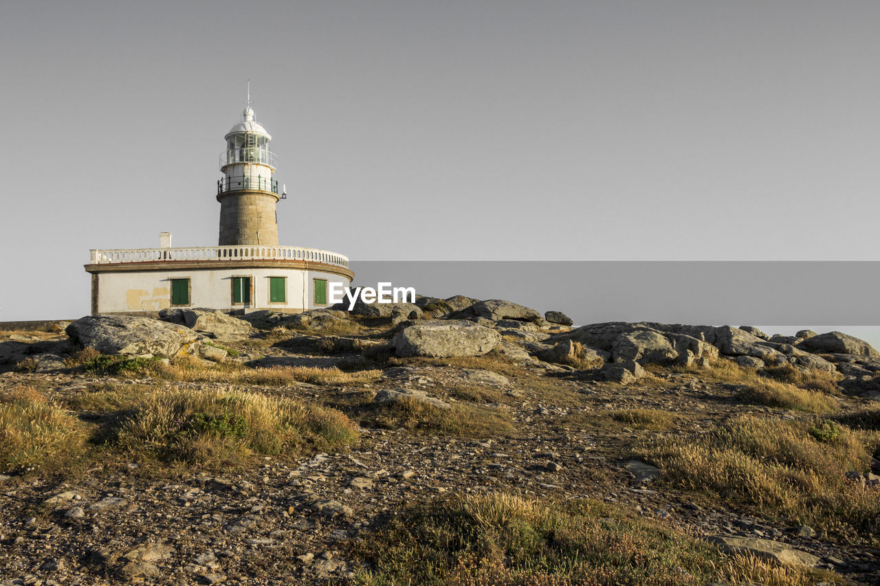 Lighthouse on field against clear sky