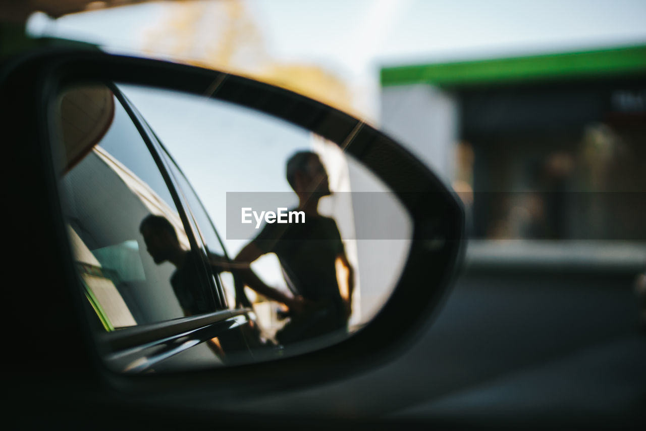 Reflection of man on side-view mirror