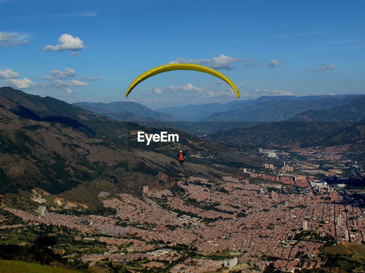 Person doing paragliding over mountain against sky
