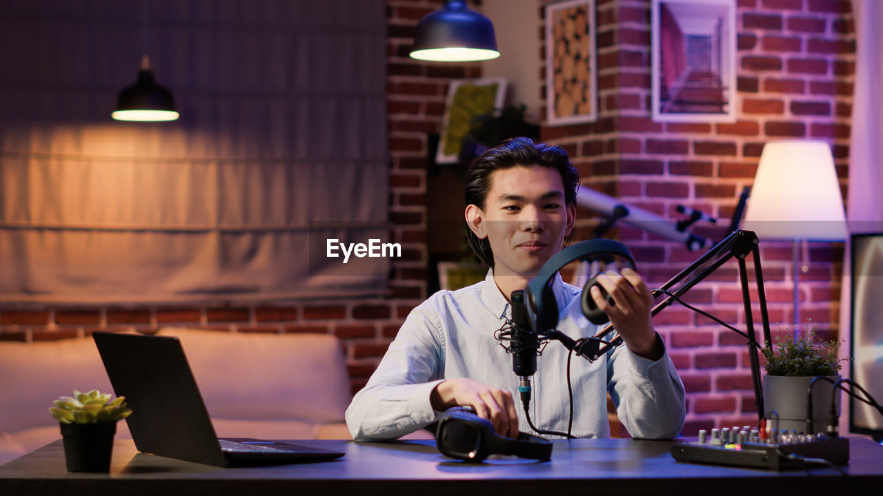 Smiling man holding headphones at recording studio