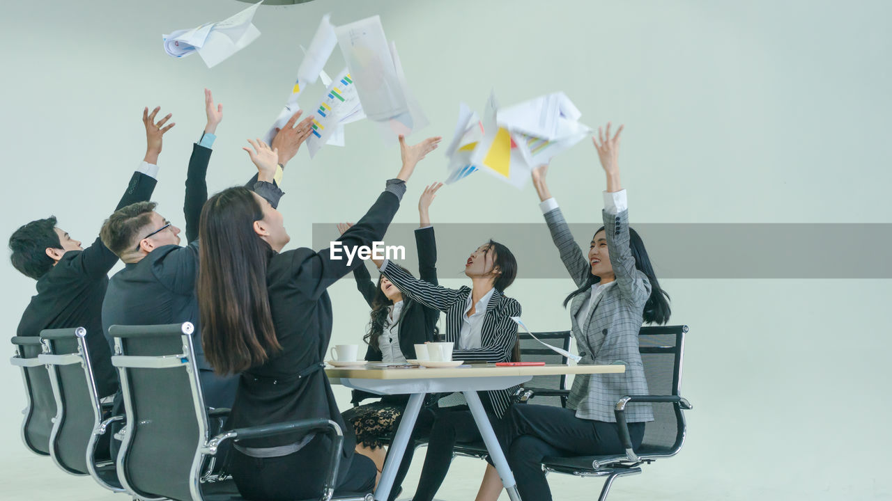 Cheerful business people throwing papers while sitting in office