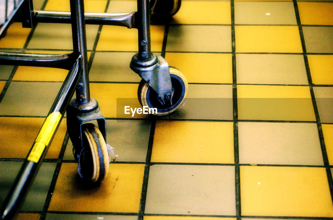 Close-up of cropped shopping trolley on tiled floor