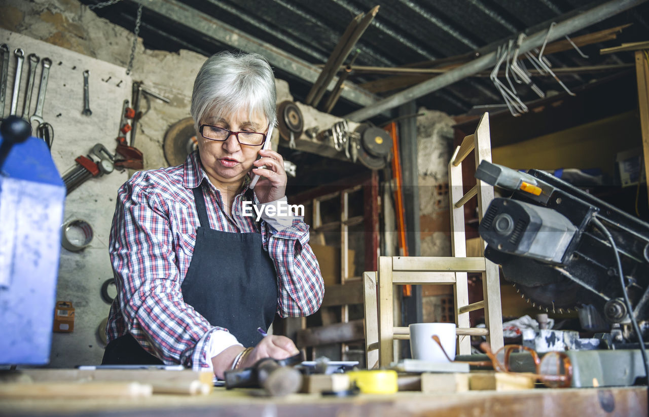 Senior woman talking over mobile phone in workshop