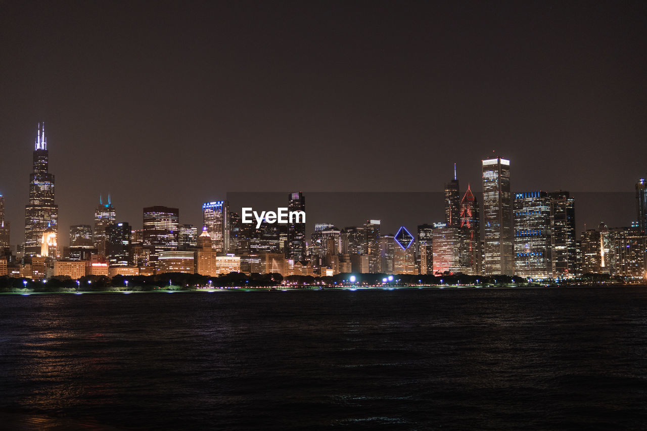 Illuminated buildings in city against sky at night