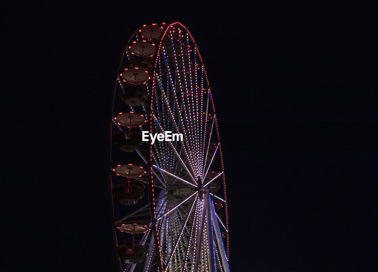 Low angle view of illuminated ferris wheel against sky at night