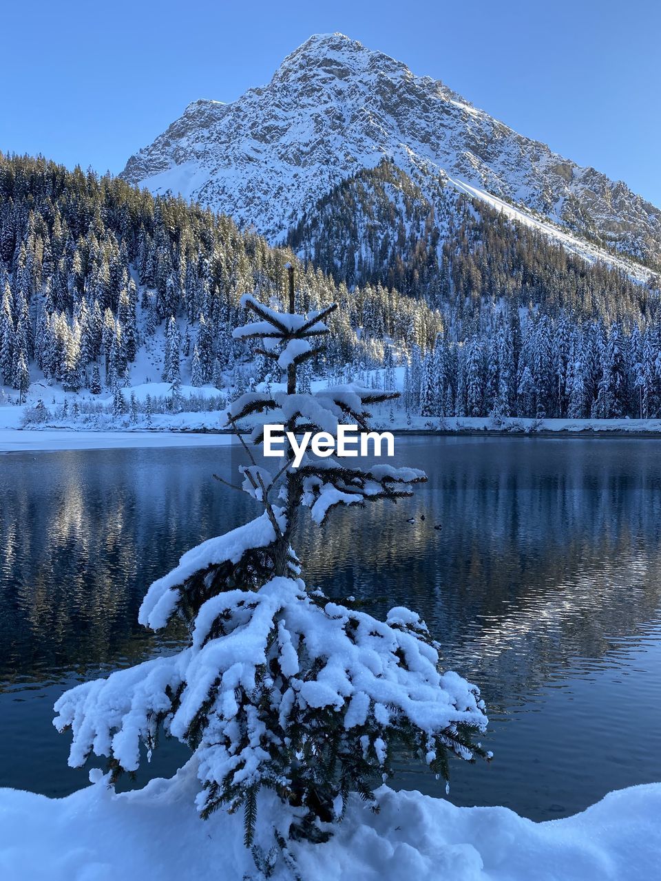 Frozen lake by snowcapped mountain against sky