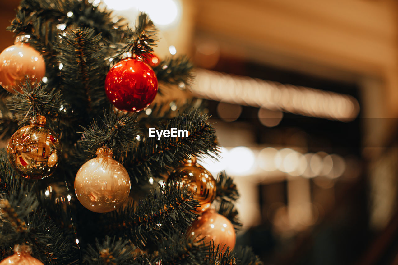 Golden and red christmas balls hanging on the christmas tree. bokeh magic effect. festive winter