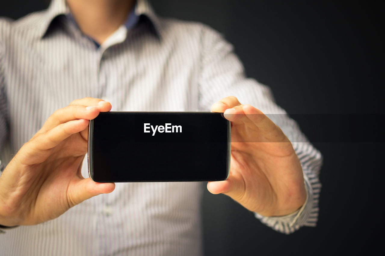 Close up of businessman showing empty touchscreen of his cell phone towards the camera. copy space.