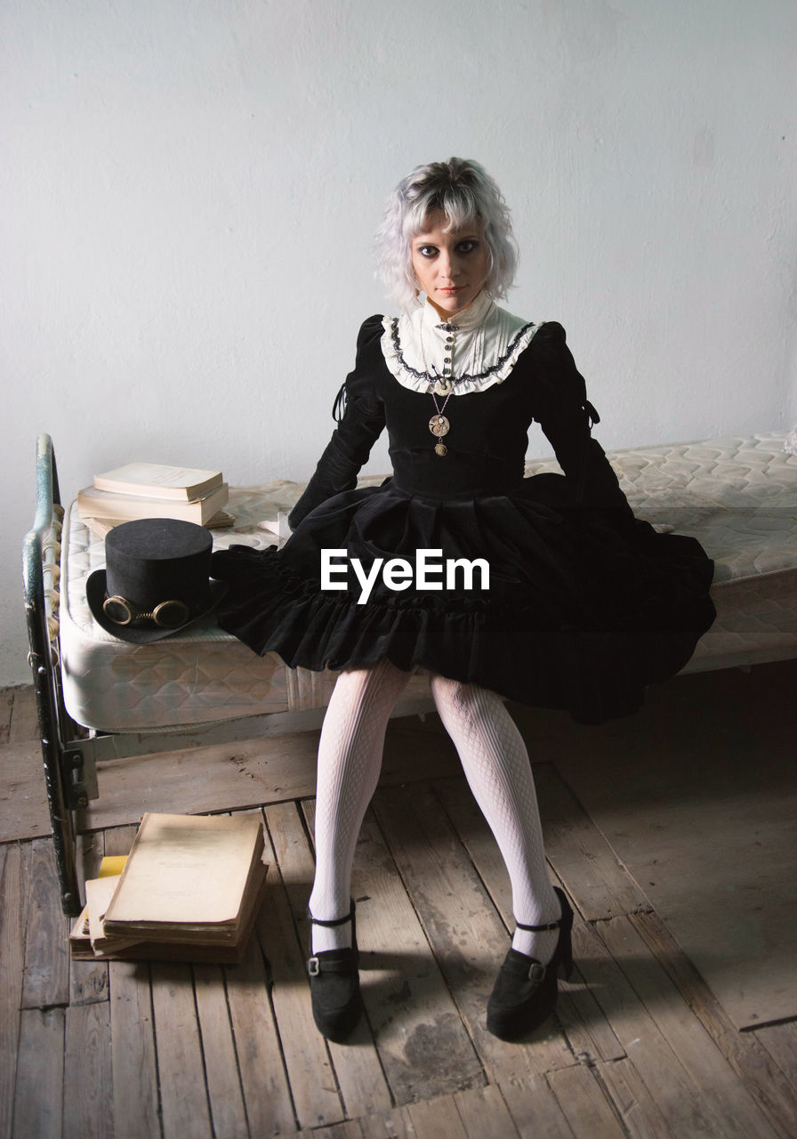 Portrait of woman wearing costume while sitting on bed at home