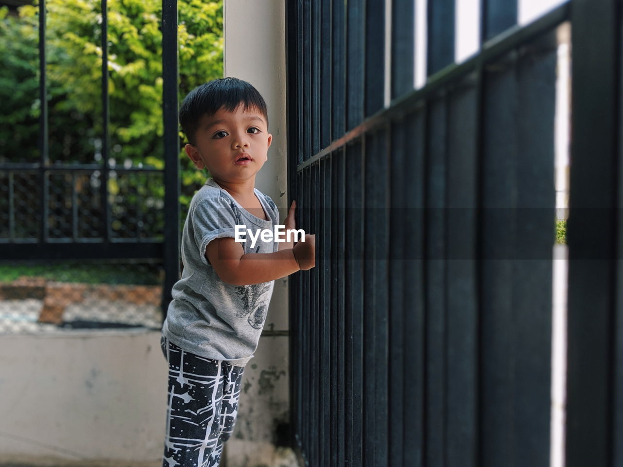 Cute boy looking away while standing by railing