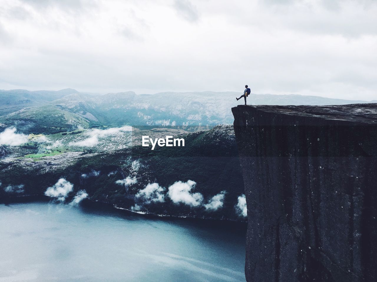 Mid distance view of person standing at the edge of cliff by sea