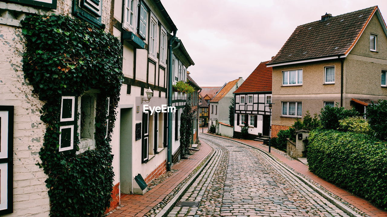 Footpath amidst houses and buildings against sky