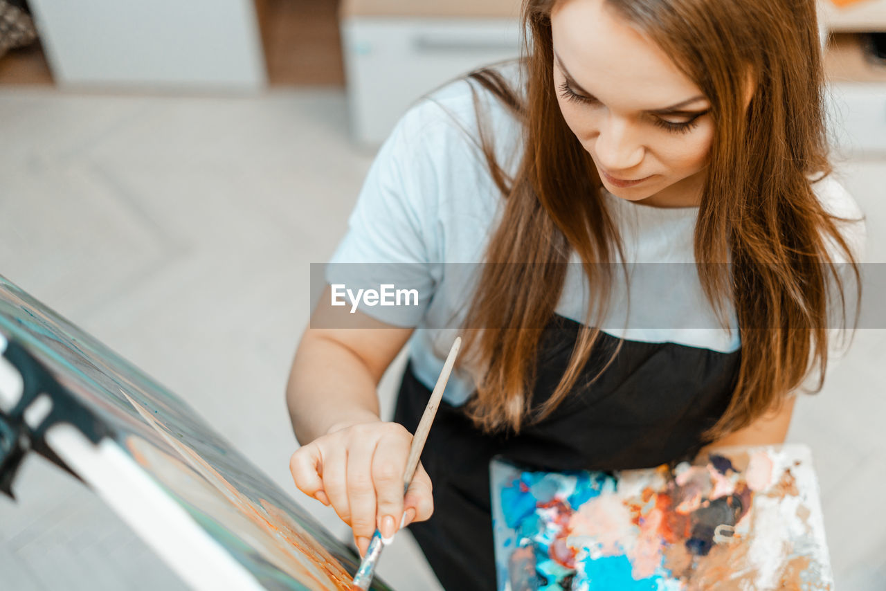 High angle view of beautiful woman painting on canvas