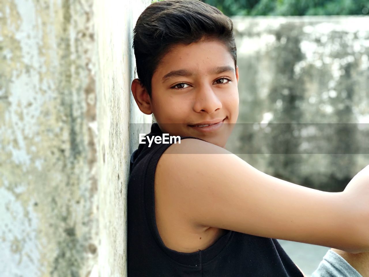 Side view portrait of smiling boy sitting outdoors