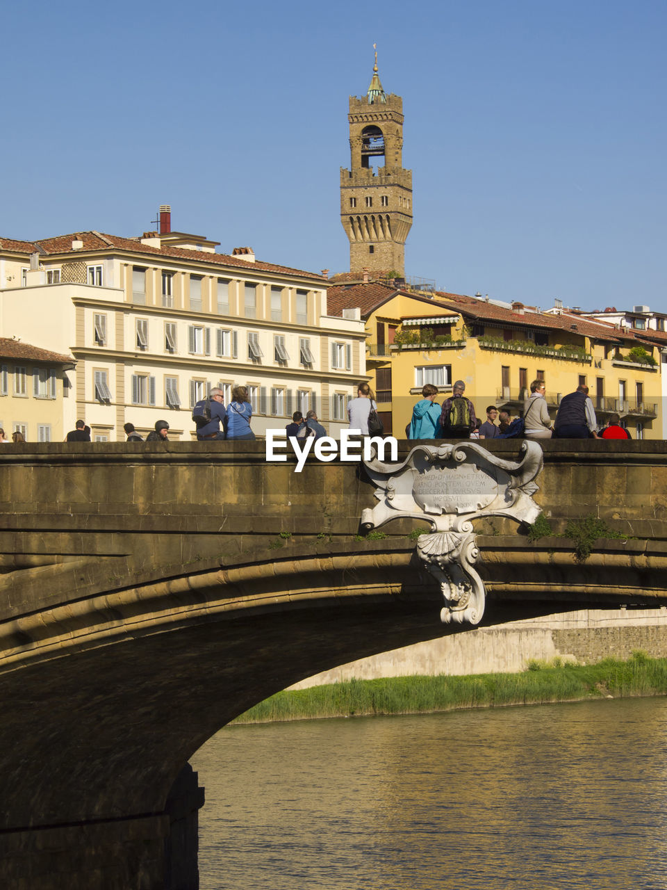 People at ponte santa trinita bridge against buildings