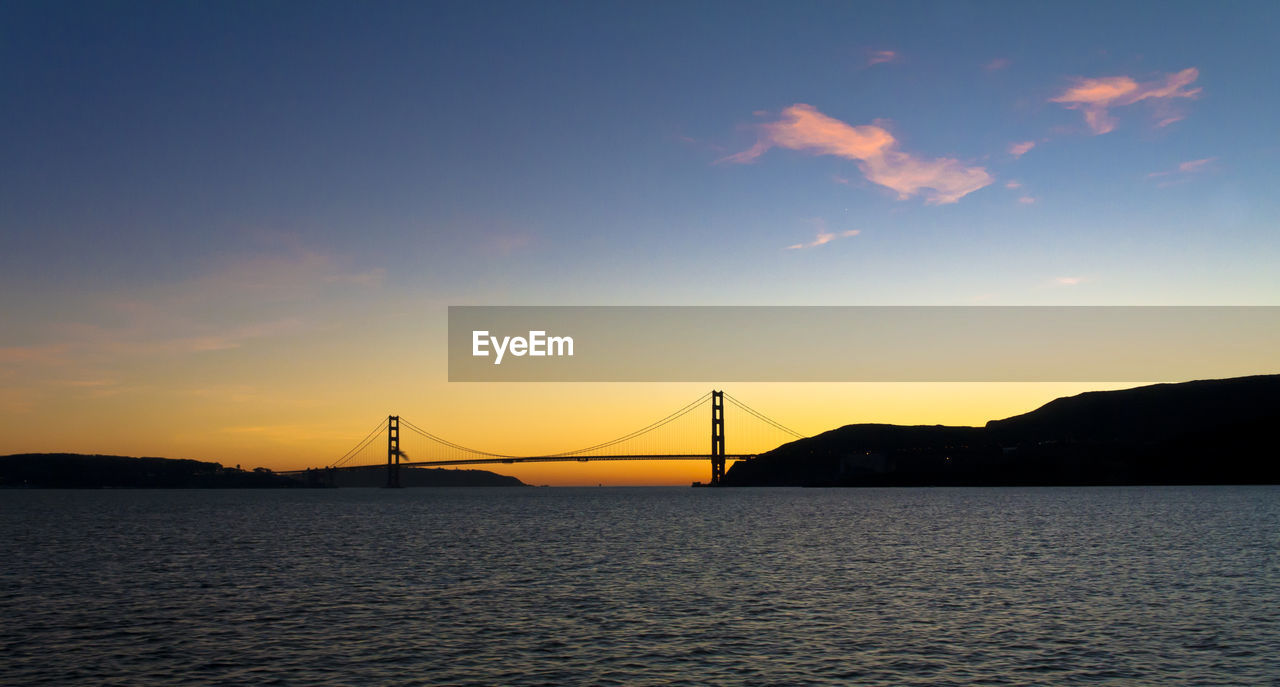 Silhouette golden gate bridge over sea against sky during sunset