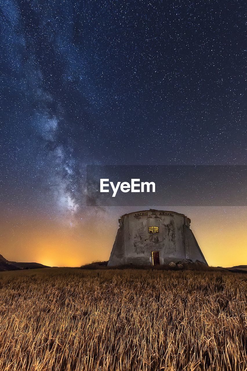 Built structure on field against sky at night
