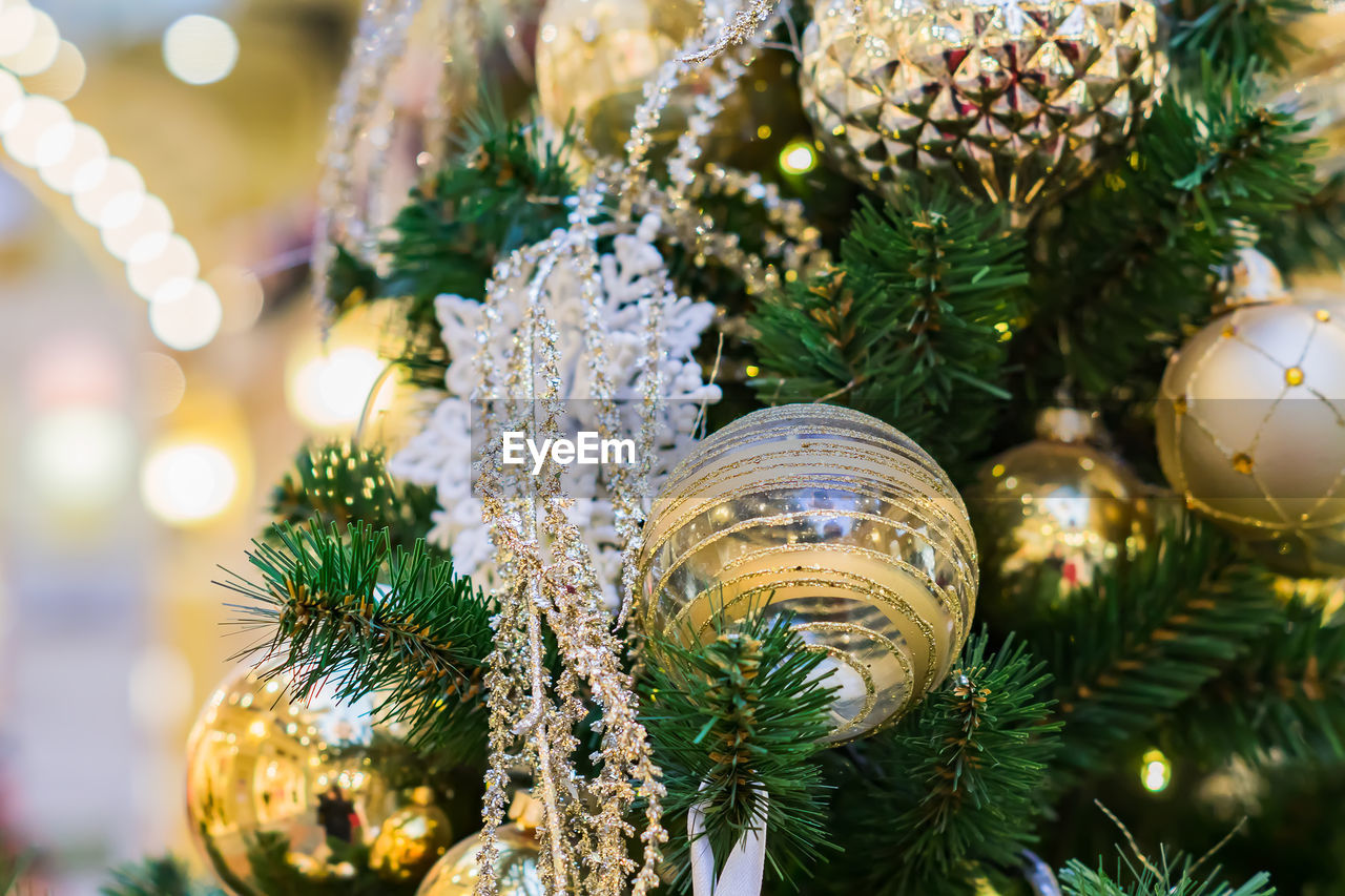 Close up of christmas tree decorated with gold and white balls and snowflake. new year background