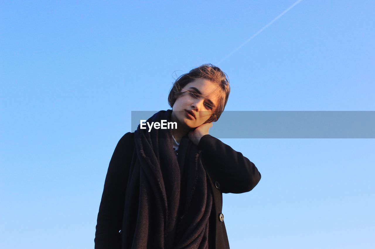 Portrait of young woman against clear sky