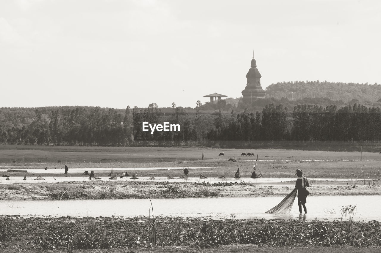 MAN ON FIELD AGAINST BUILDINGS