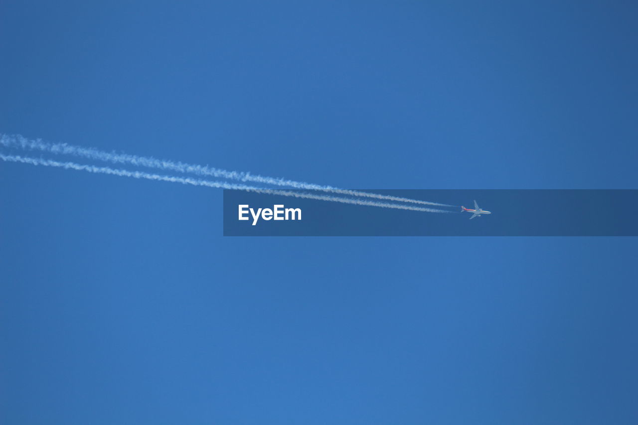 Low angle view of airplane flying against clear blue sky