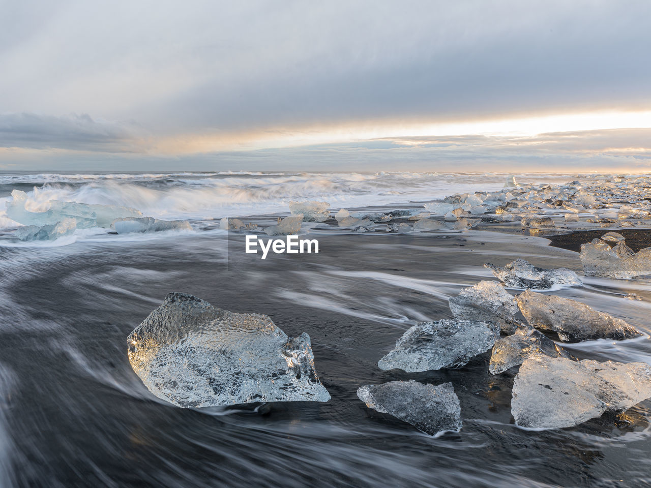 Long exposition of diamond beach, iceland, at sunset, with waves and ice formations