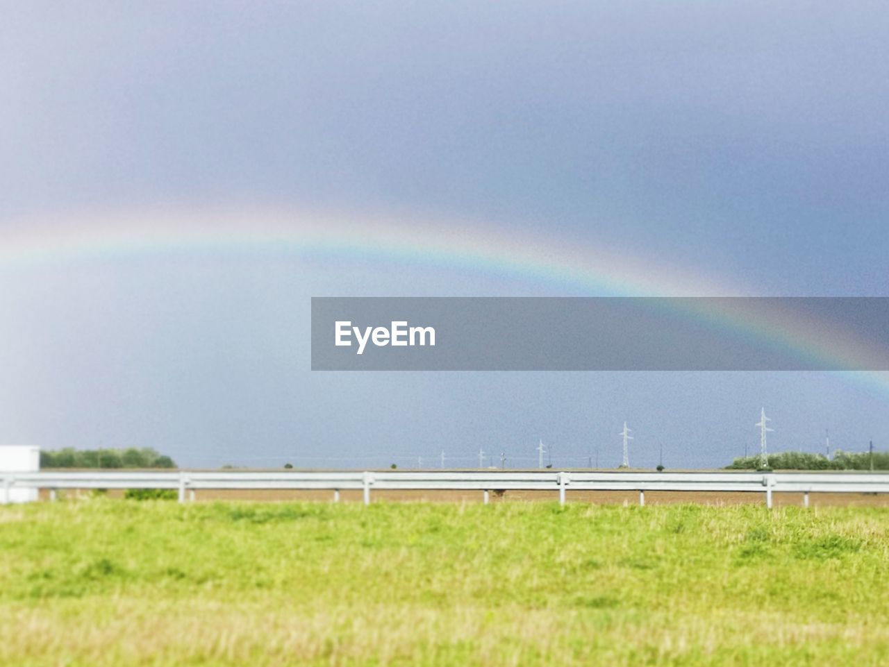 RAINBOW OVER FIELD AGAINST SKY