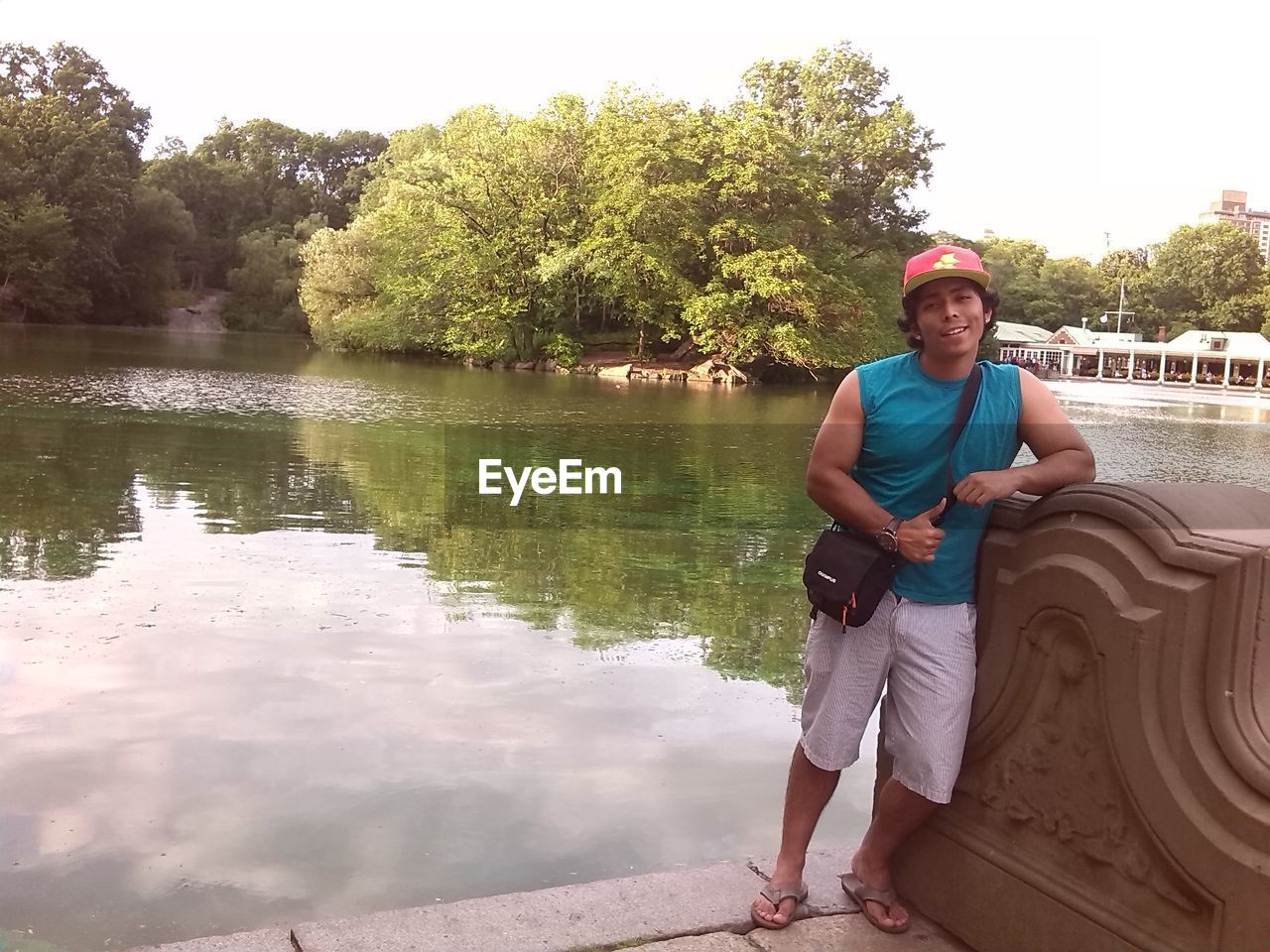 FULL LENGTH PORTRAIT OF YOUNG MAN STANDING BY LAKE