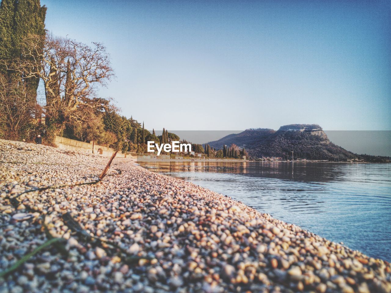 PEBBLES ON SHORE AGAINST CLEAR SKY