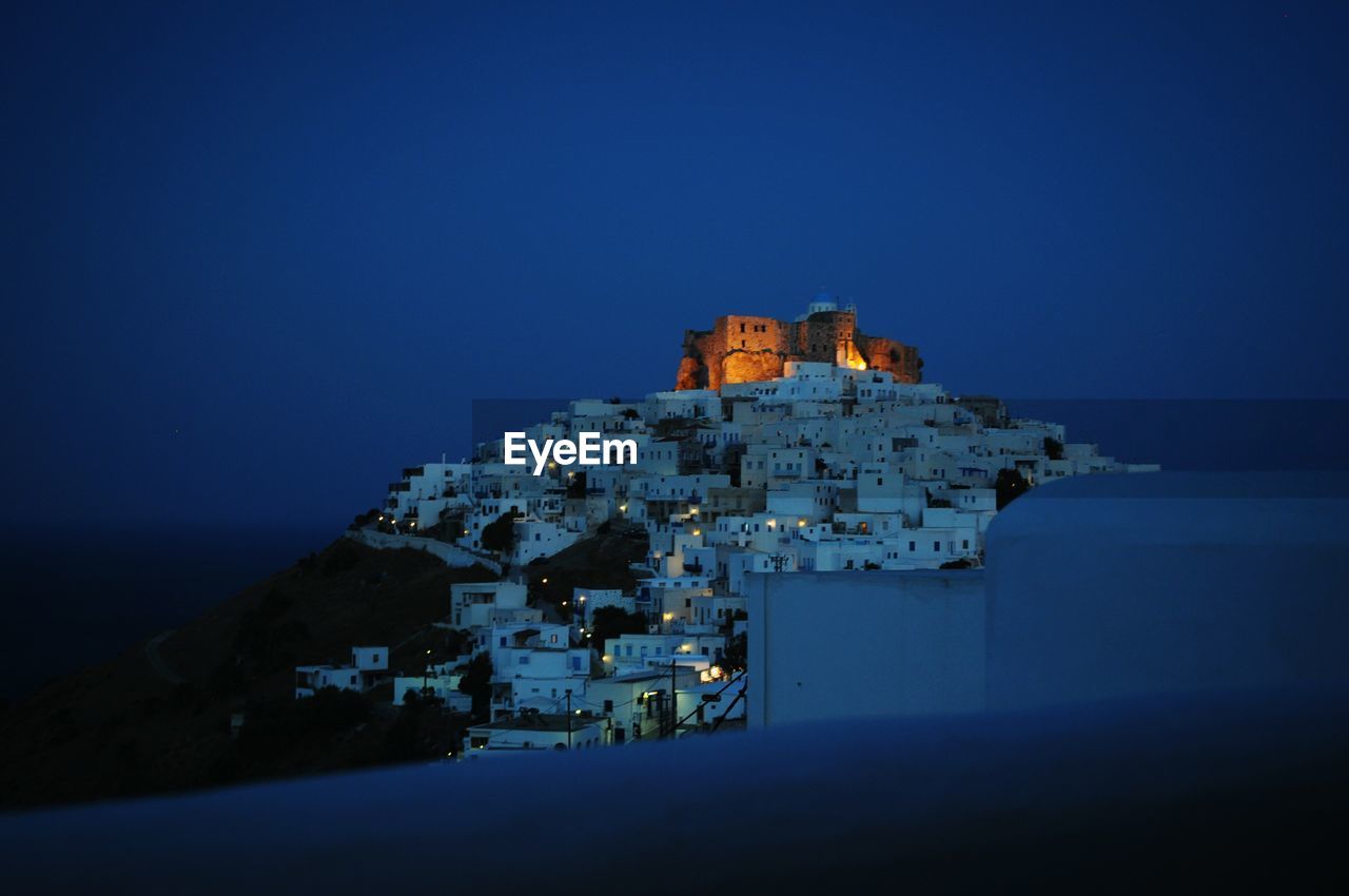 Castle and buildings against blue sky at night