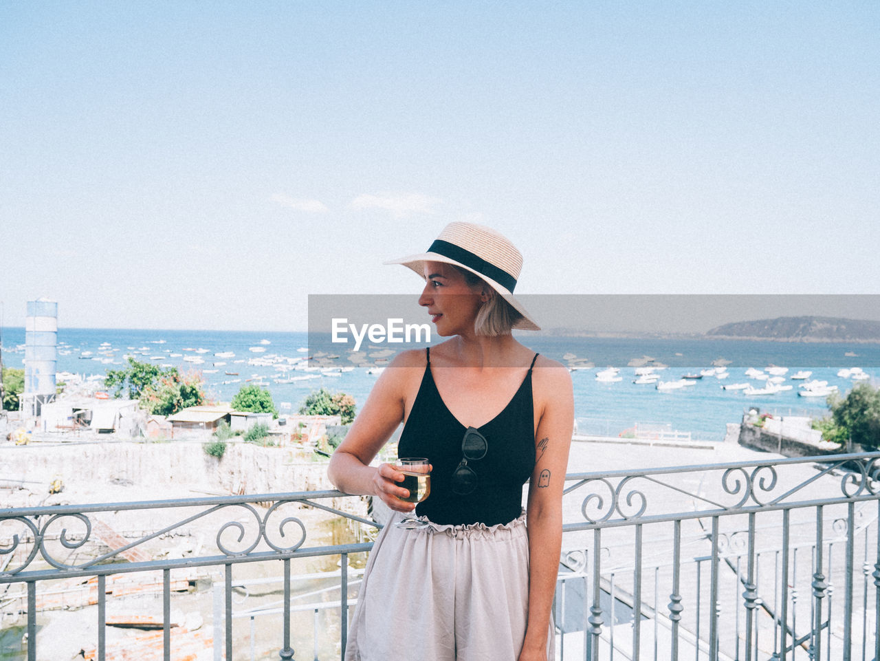 YOUNG WOMAN LOOKING AWAY WHILE STANDING BY RAILING