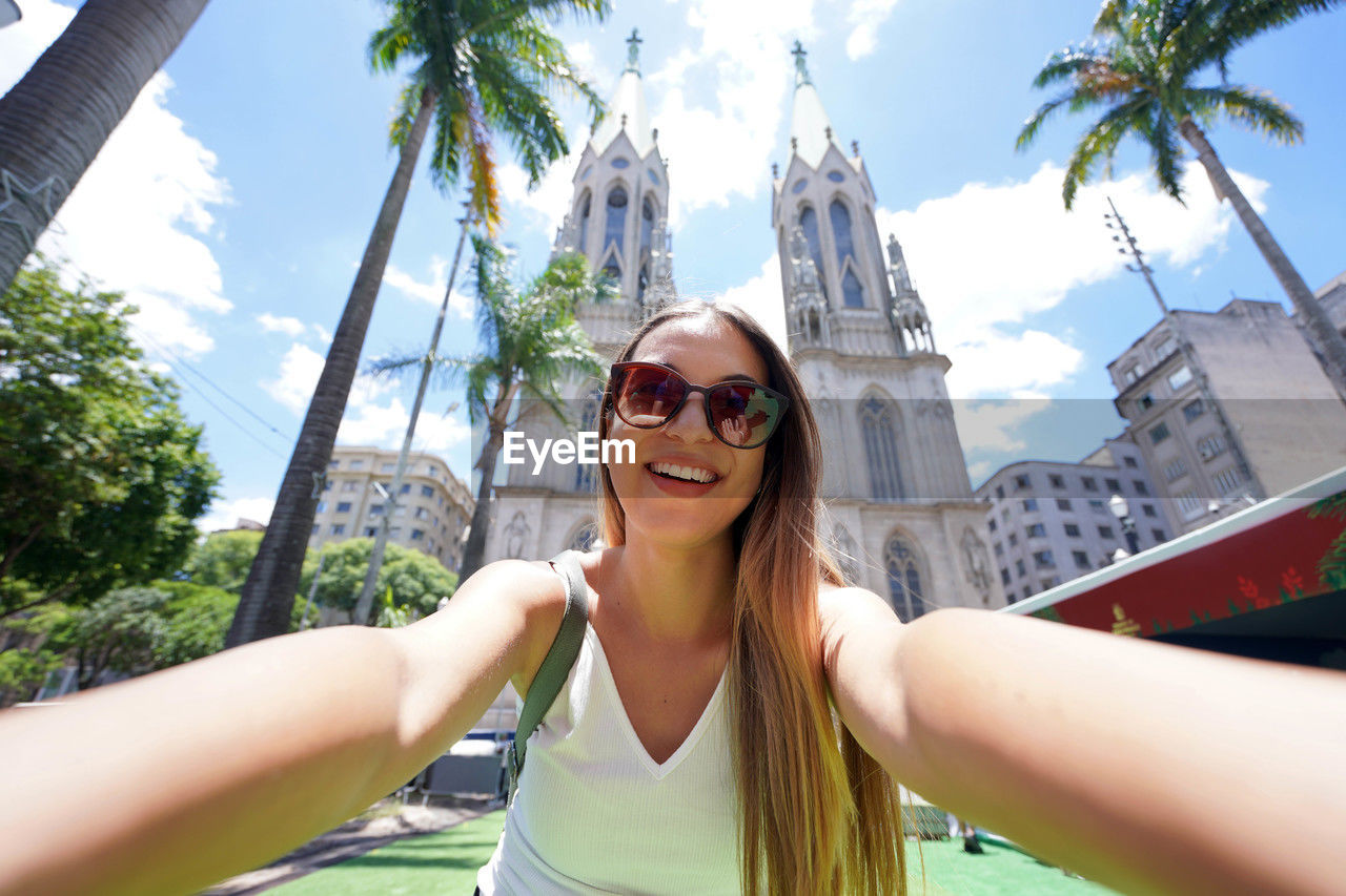 Smiling tourist girl takes self portrait with sao paulo cathedral on the background, brazil