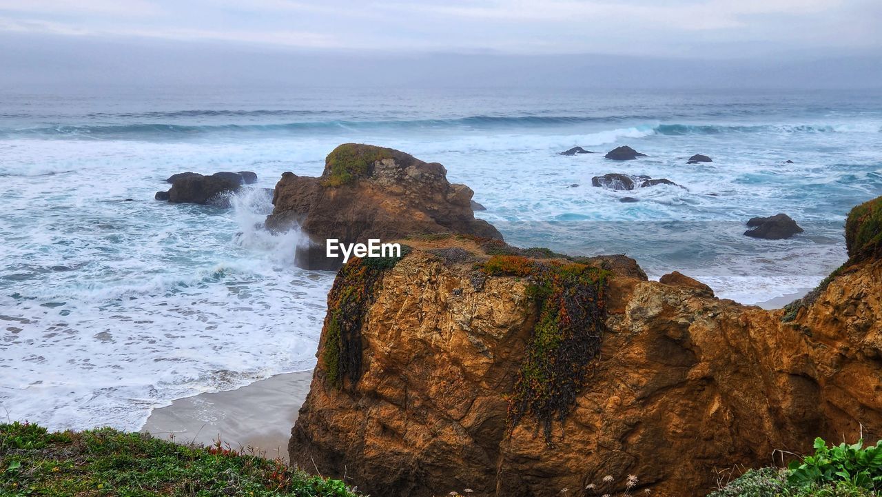 sea, water, rock, land, beach, shore, body of water, coast, cliff, ocean, beauty in nature, scenics - nature, sky, wave, nature, terrain, motion, coastline, wind wave, cloud, environment, horizon, cove, bay, travel destinations, landscape, sports, no people, rock formation, travel, horizon over water, seascape, outdoors, water sports, tranquility, tourism, trip, day, coastal feature, holiday, rocky coastline, idyllic, vacation, tranquil scene