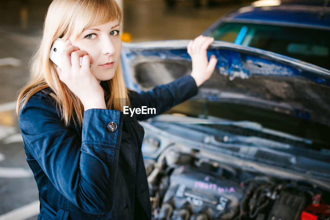 Portrait of woman talking on mobile phone by car