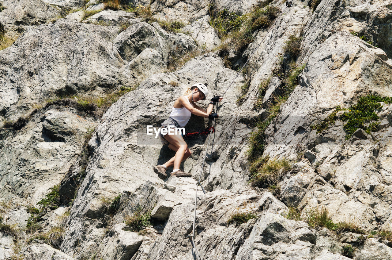 Low angle view of woman climbing rock