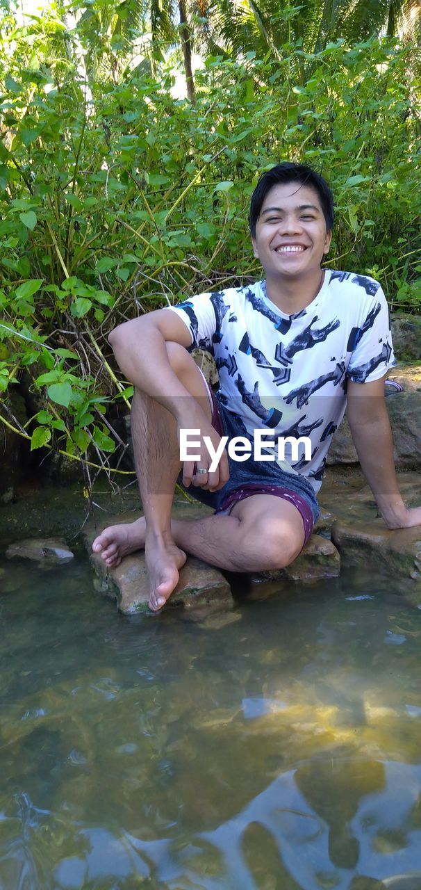 portrait of smiling young man sitting in water