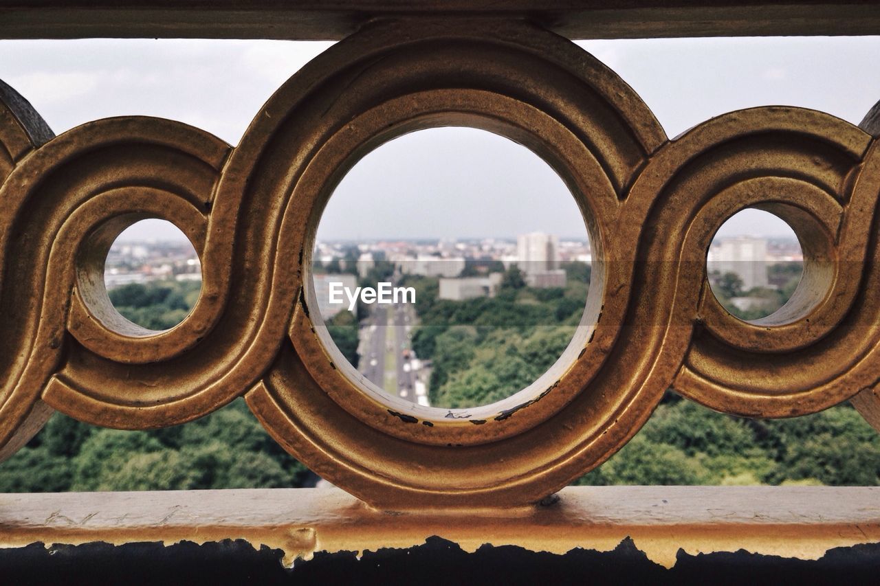 City scape viewed through a hole on the ornament of a fence