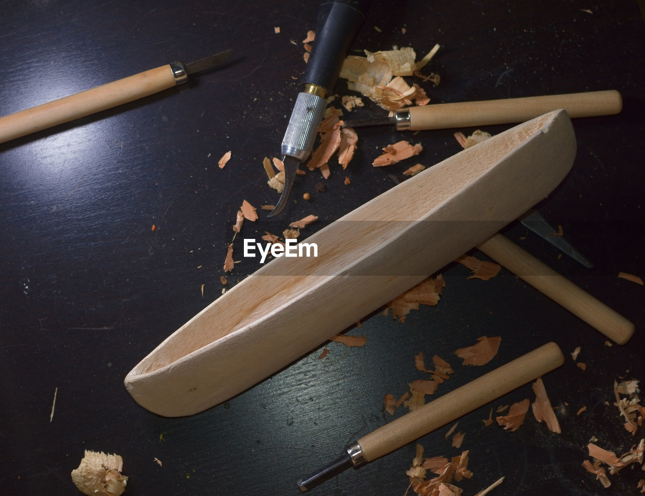 High angle view of hand tool and carved wooden structure on table