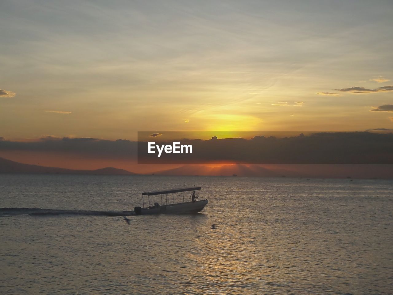 SILHOUETTE OF BOAT IN SEA AT SUNSET