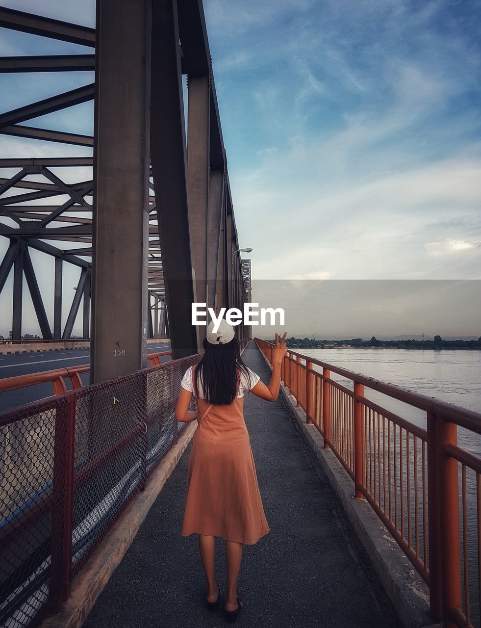 Rear view of woman standing on bridge against sky